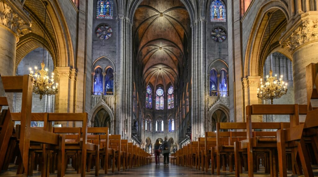 Interior of Notre Dame Cathedral showing the nave, Gothic arches and stained glass rose windows after the 2024 restoration