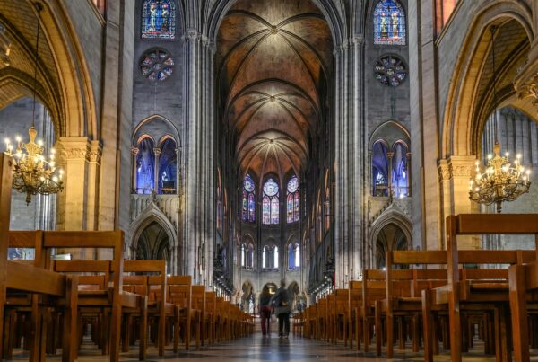 Interior of Notre Dame Cathedral showing the nave, Gothic arches and stained glass rose windows after the 2024 restoration