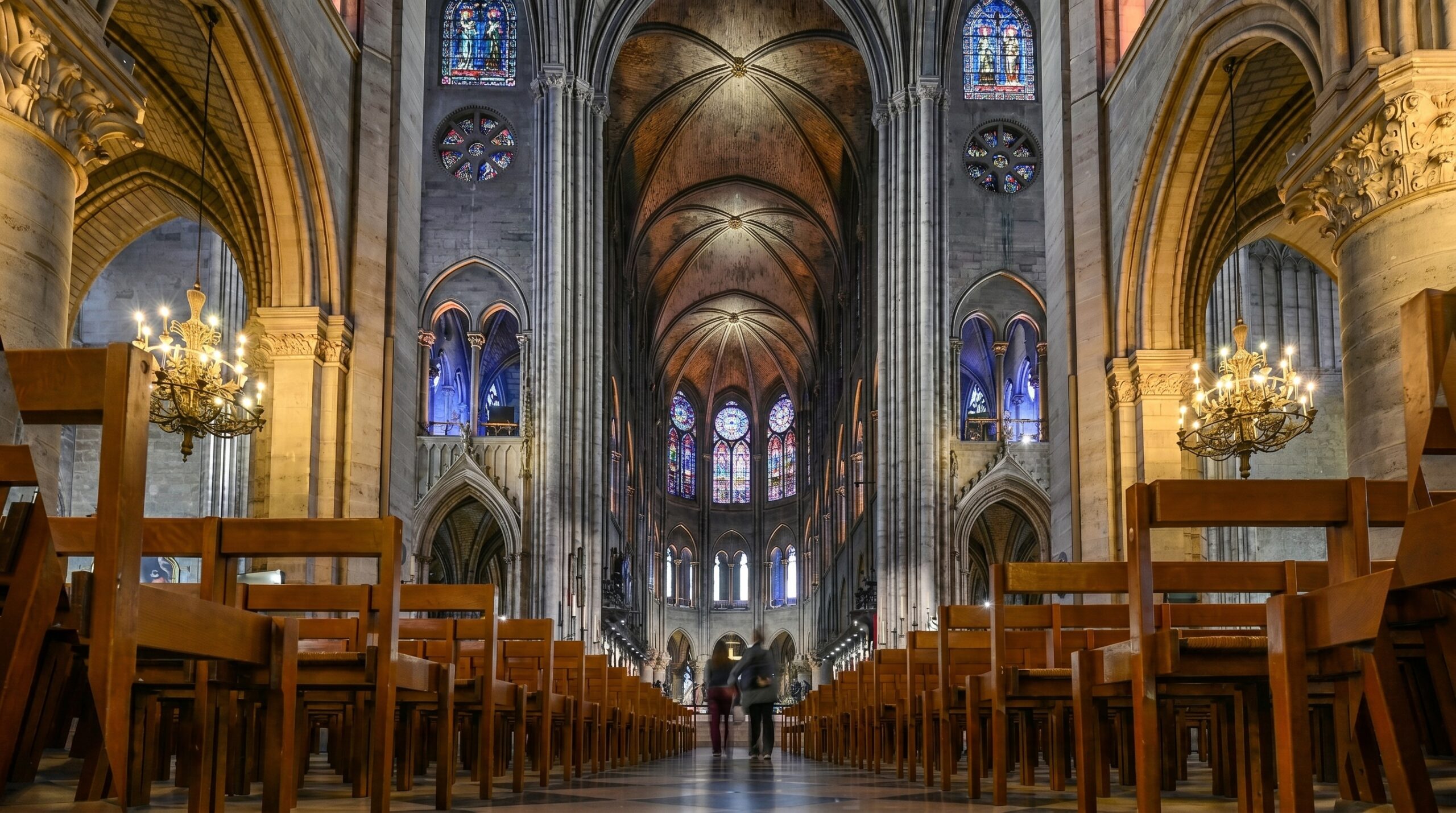 Interior of Notre Dame Cathedral showing the nave, Gothic arches and stained glass rose windows after the 2024 restoration